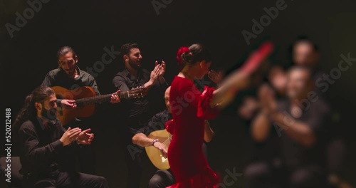 Beautiful stylish female artist dancing spanish style dance . Group of men playing on guitar and applauds to the dancer woman . Concept footage of spanish traditional culture . Waving cloth of skirt photo