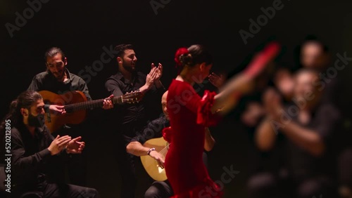 Beautiful stylish female artist dancing spanish style dance . Group of men playing on guitar and applauds to the dancer woman . Concept footage of spanish traditional culture . Waving cloth of skirt 