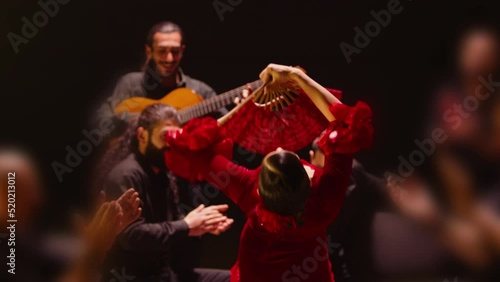 Beautiful stylish female artist dancing spanish style dance . Group of men playing on guitar and applauds to the dancer woman . Concept footage of spanish traditional culture . Waving cloth of skirt 