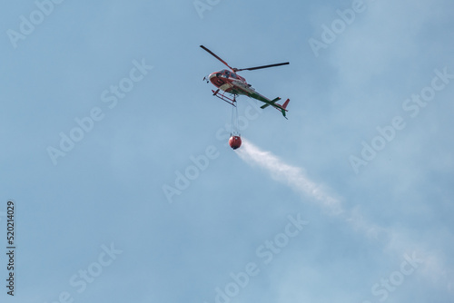 Hélicoptère pompier chargé d'une réserve d'eau intervenant sur le lieu d'un incendie de forêt