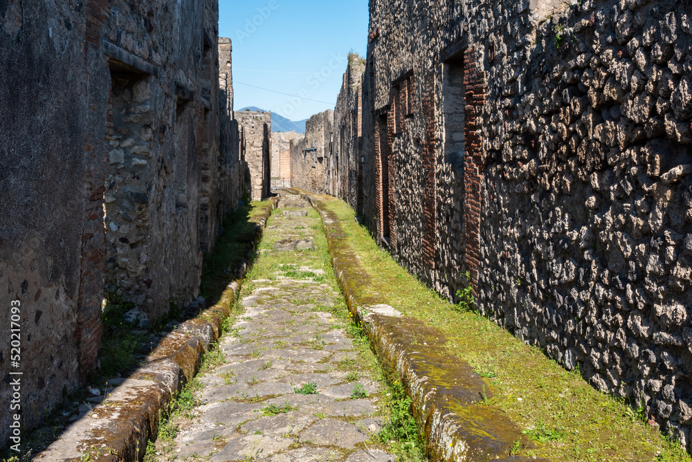 POMPEII, ITALY - MAY 04, 2022 - A beautiful typical cobbled street in the ancient city of Pompeii, Italy POMPEII, ITALY - MAY 04, 2022 - A beautiful typical cobbled street in the ancient city of Pompeii, Italy