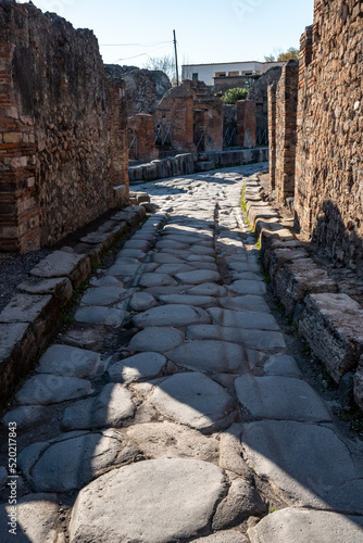 Fototapeta Naklejka Na Ścianę i Meble -  POMPEII, ITALY - MAY 04, 2022 - A beautiful typical cobbled street in the ancient city of Pompeii, Italy