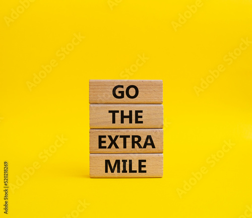 Go the extra mile symbol. Wooden blocks with words Go the extra mile. Beautiful yellow background. Business and Go the extra mile concept. Copy space.