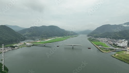 Aerial swoop into unfinished bridge span and small town amid mountain landscape photo