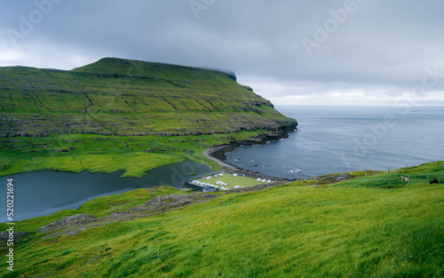 View of an old soccer field with a picturesque cliff on the coast near the village of Eidi in the Faroe Islands. This football stadium is now used as a campsite.