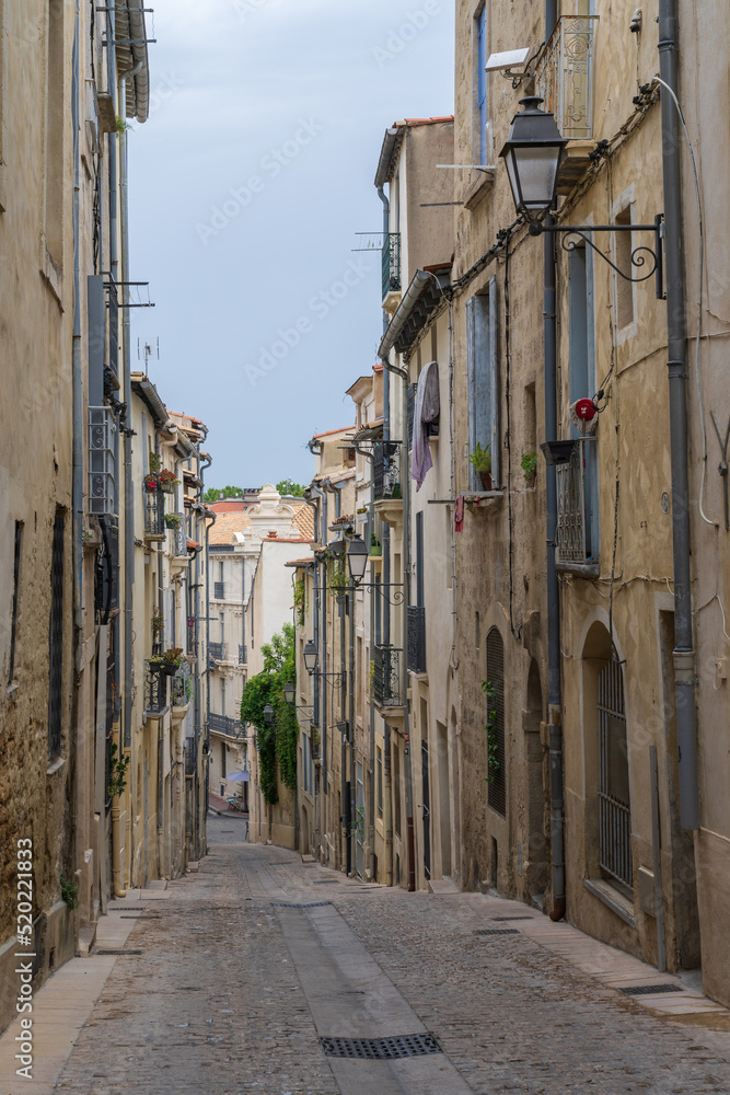 Scenic urban landscape view of typical narrow cobblestone street with ancient buildings in the historic center of Montpellier, France