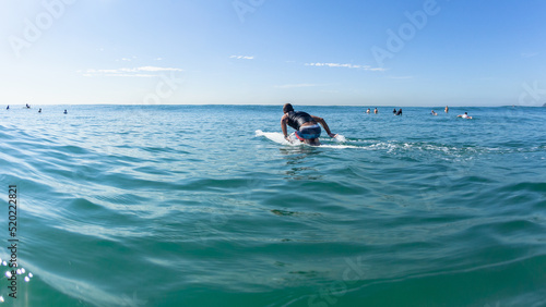 Surfer Paddling Long Surfboard Board Ocean Towards Blue Sky Horizon.