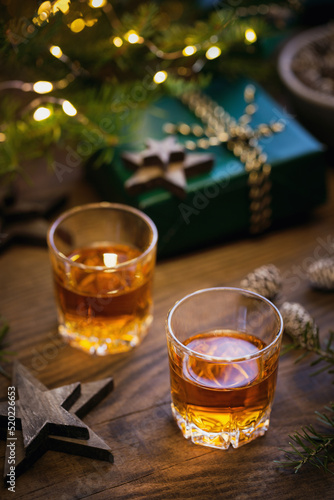 Two glasses of whiskey or bourbon with Christmas decoration on dark background. New Year, Christmas and winter holidays whiskey mood concept