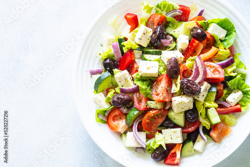 Greek salad. Vegetable salad with tomato, cucumber, feta cheese, greek olives and olive oil. Top view, close up.