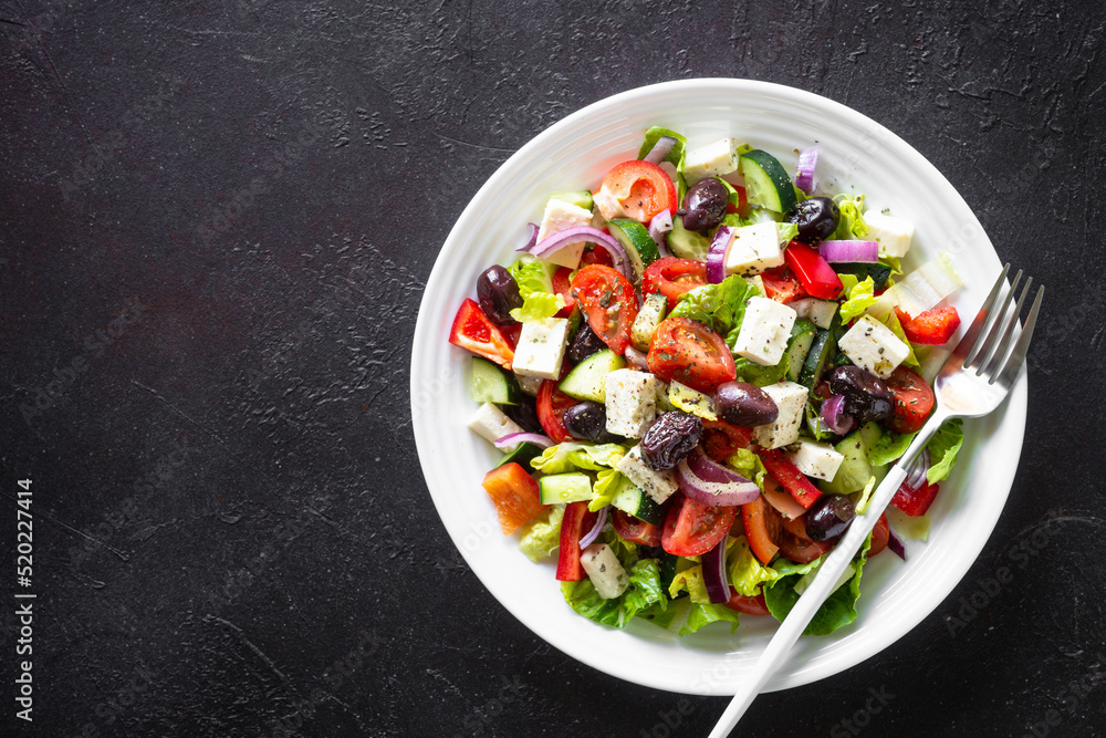 Greek salad. Vegetable salad with tomato, cucumber, feta cheese and olive oil. Top view on black stone table. Greek salad. Vegetable salad with tomato, cucumber, feta cheese and olive oil. Top view on black stone table.