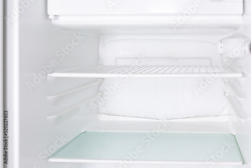 a frozen refrigerator that needs to be defrosted. Block of ice in the empty fridge. empty shelves in the refrigerator. Refrigerator maintenance. frozen Ice buildup in the freezer of refrigerator