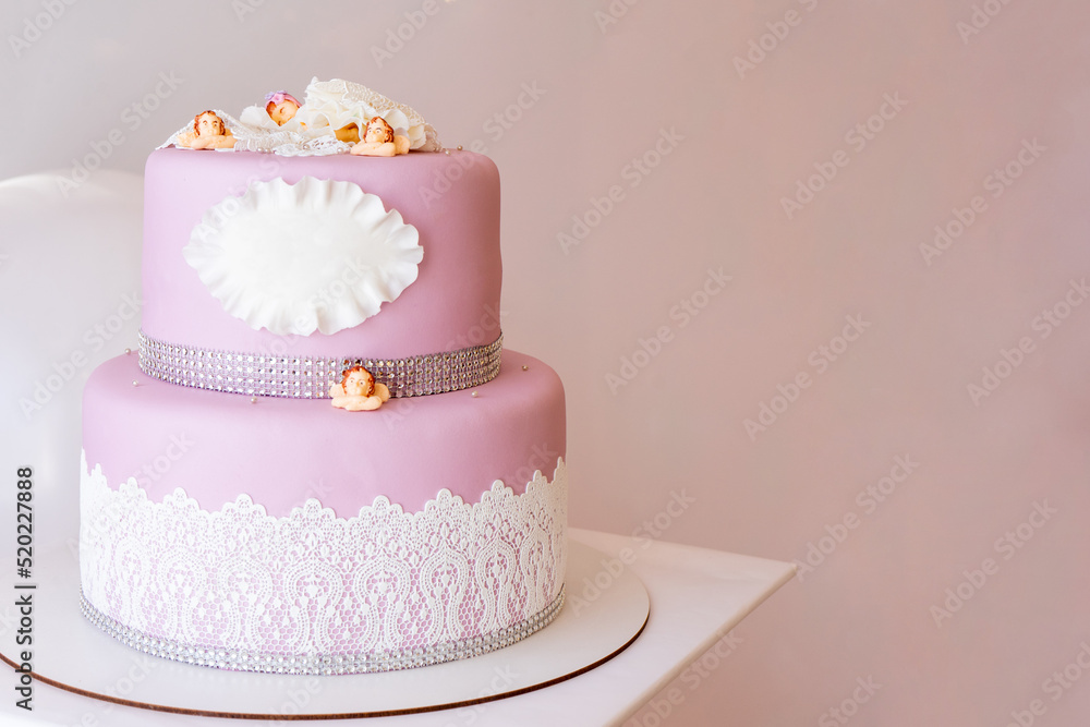 Two-tiered pink cake with a place for an inscription and little angels. Copy space Two-tiered pink cake with a place for an inscription and little angels. Copy space