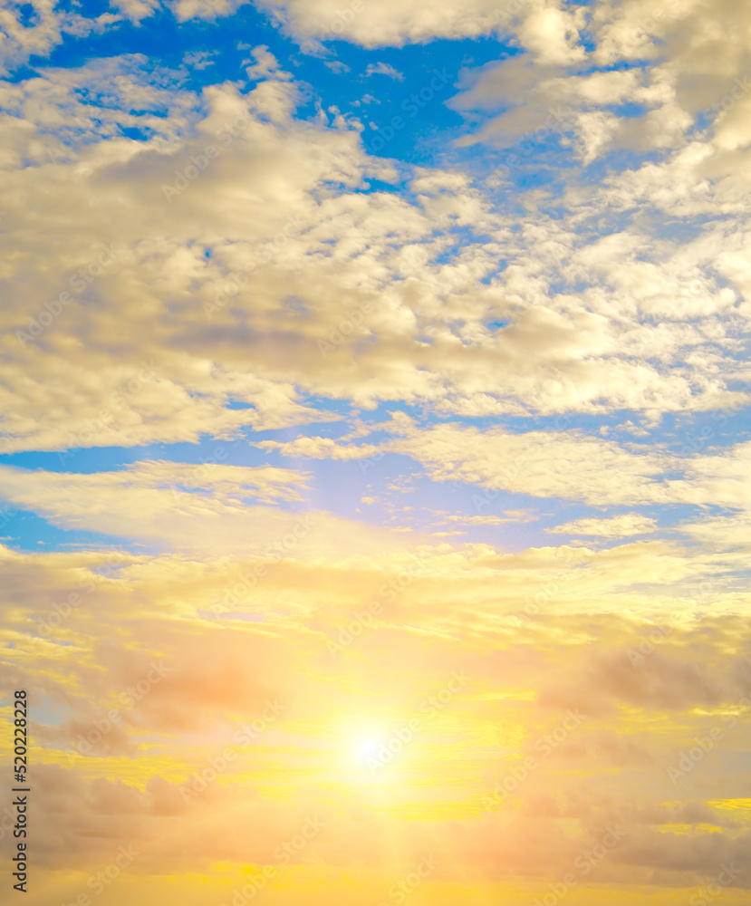 Beautiful sky with a bright sunset (rise) of the sun and light clouds. Vertical photo.