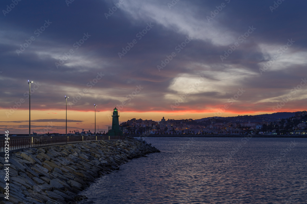 Dramatic colorful clouds at sunset with cityscape silhouette, Imperia, Liguria, Italy