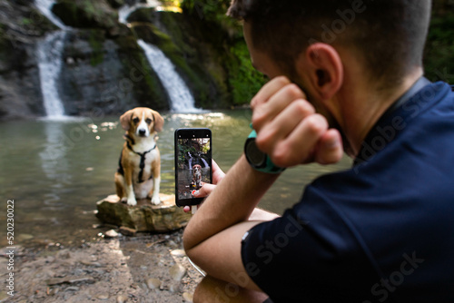 Fototapeta a man takes a photo of a dog near a waterfall