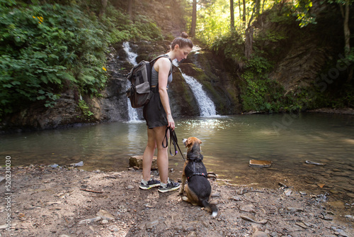 young woman with a dog near a waterfall