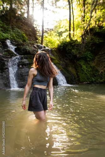 a young woman stands near a waterfall