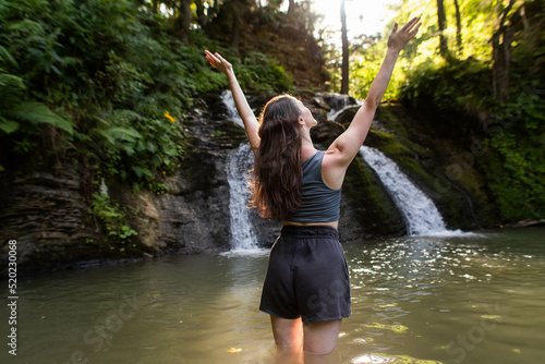 a young woman stands near a waterfall