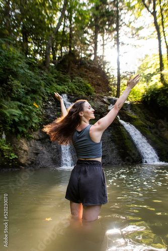 Fototapeta Naklejka Na Ścianę i Meble -  a young woman stands near a waterfall