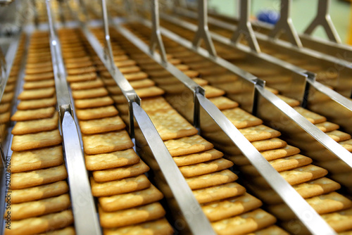 A lot of cookies on the production line. The flow of sweets before packaging. Packing crackers on the machine. Innovative production.