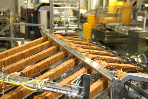 A lot of cookies on the production line. The flow of sweets before packaging. Packing crackers on the machine. Innovative production. © neznamov1984