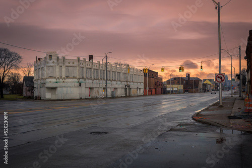 Looking down a wide avenue with abandoned buildings in urban Detroit with dramatic sky