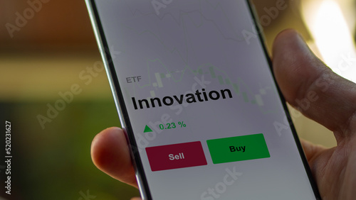 Un investisseur analyse un fonds etf innovation sur un graphique. Un téléphone affiche le cours de l'ETF innovant.