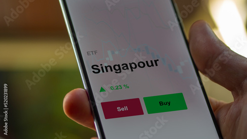 Un investisseur analyse un fonds etf singapour sur un graphique. Un téléphone affiche le cours de l'ETF. Texte en français francais Singapour