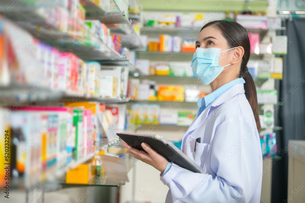 Portrait of female pharmacist wearing face mask in a modern pharmacy drugstore.