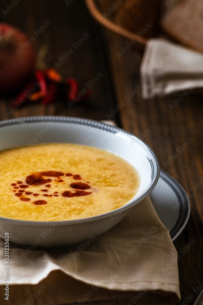 Turkish traditional lentil soup mercimek corbasi with melted butter and red pepper sauce on wooden background. Low-key food photography. Turkish traditional lentil soup mercimek corbasi with melted butter and red pepper sauce on wooden background. Low-key food photography.