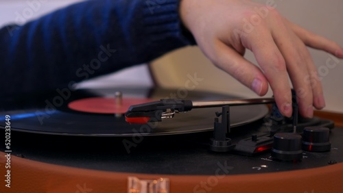 Close-up put a vinyl record in the turntable and lower the needle to listen to classical music. A vintage turntable that spins a vinyl record. Listening to music in the 20th century.