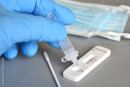 closeup of a healthcare worker hand in blue surgical gloves while taking a test for the covid-19 virus showing a negative result. Protective mask on the background. selective focus