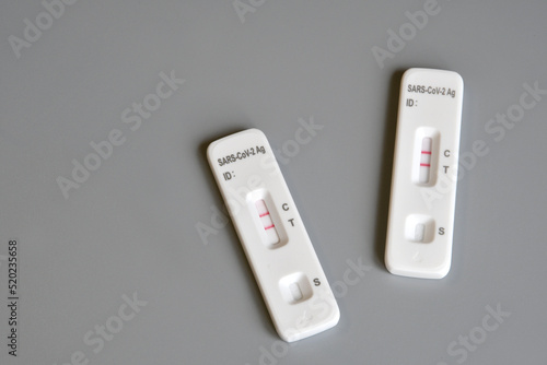 two SARS‑CoV‑2 antigen test kit for self testing with positive results. One step coronavirus antigen rapid test, saliva swab on grey background. close-up