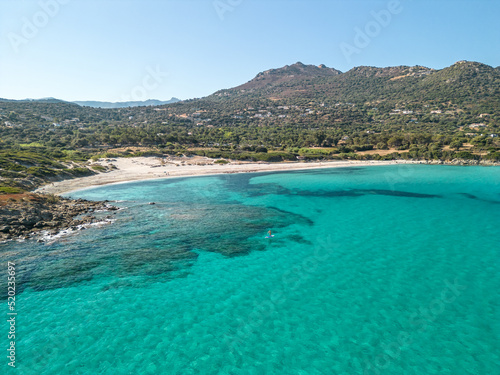 Aerial view of a paddle boarder on a clear turquoise Mediterranean sea at Bodri beach in the Balagne region of Corsica