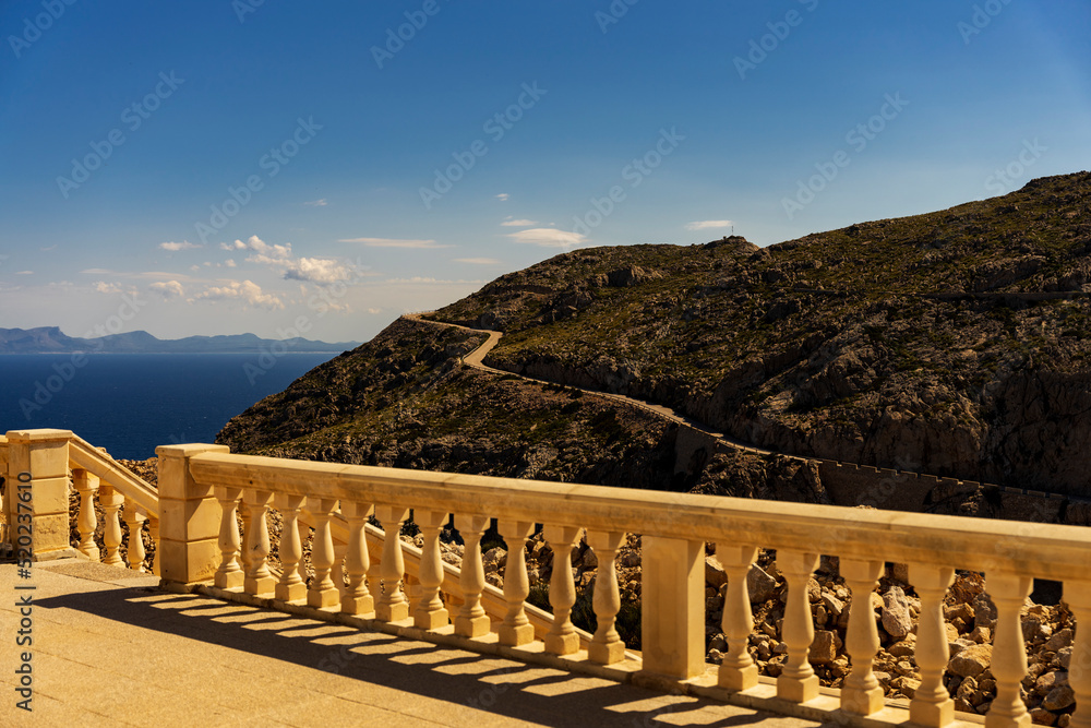 Krajobraz górski, widok na zdobione kamienne barierki przy latarni Cap de Formentor, w tle górskie wybrzeże, Majorka, Hiszpania. - obrazy, fototapety, plakaty 