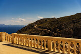 Krajobraz górski, widok na zdobione kamienne barierki przy latarni Cap de Formentor, w tle górskie wybrzeże, Majorka, Hiszpania.