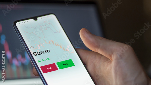 Un investisseur analyse un fonds etf cuivre sur un graphique. Un téléphone affiche le cours de l'ETF. Texte en français francais Cuivre