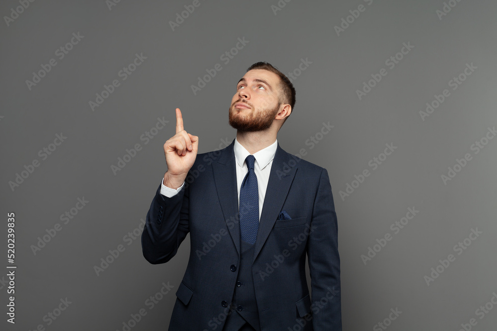 Young business man pointing up against gray wall banner background Young business man pointing up against gray wall banner background