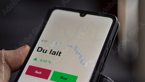 Un investisseur analyse un fonds etf du lait sur un graphique. Un téléphone affiche le cours de l'ETF laitier. Texte en français, francais. 