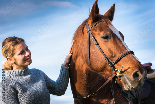 Young woman taking care of her horse
