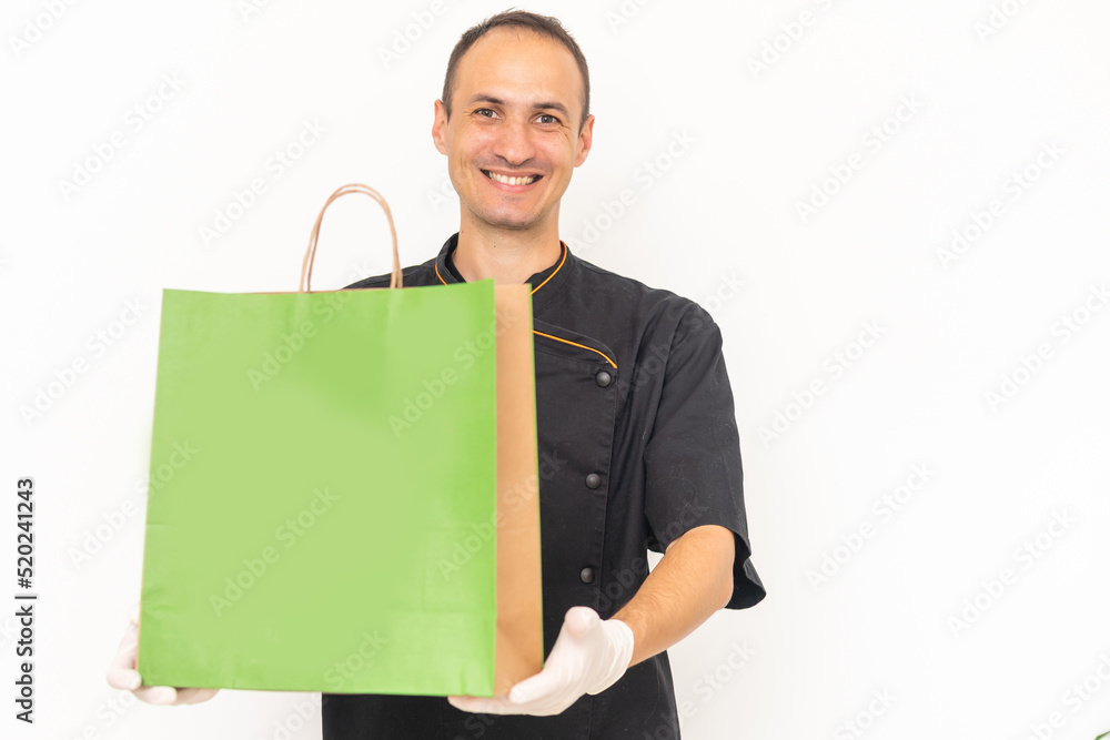 Delivery man employee in t-shirt uniform, glove hold craft paper packet with food isolated on white background. Delivery man employee in t-shirt uniform, glove hold craft paper packet with food isolated on white background.