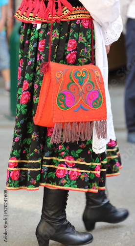 Woman in traditional folk costume from Krakow region with hand bag decorated with folklore pattern
