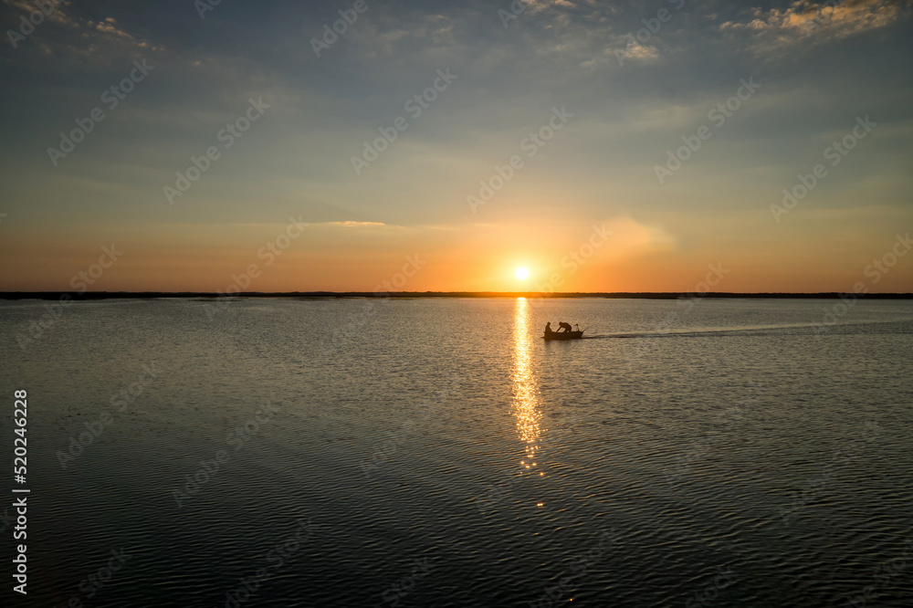 Fishermen are returning from fishing on Lake Lebsko at sunset. Cloudless sky, summer, light is reflected in the water. Pomerania, Poland, Europe.