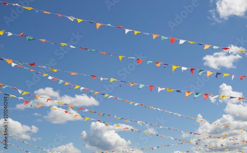 Multicolored festival flags on a blue sky background on a sunny summer day. 
