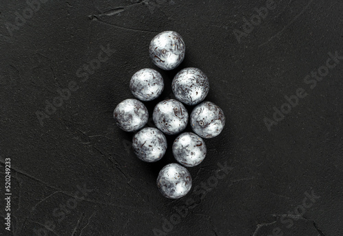 Silver candies hazelnuts in chocolate in the form of a rhombus on a dark concrete background