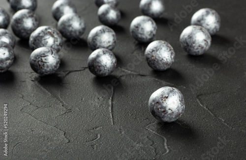 Silver candies hazelnuts in chocolate scattered on a concrete dark background