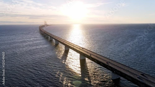 Aerial view of Oresund bridge at the sunset in summer. Cinematic shot of long bridge between Sweden and Denmark. Sunset over the sea and huge bridge. High quality 4k footage