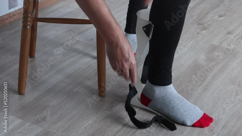 Foot drop splint for support and stabilizer ankle, someone fixes orthosis on leg.
