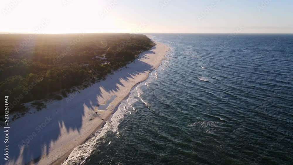 Drone flies over island with wild forest in ocean. Active sea waves come to the shore of a tropical peninsula. Dynamic aerial shot of sand beach with blue waves. High quality 4k footage Drone flies over island with wild forest in ocean. Active sea waves come to the shore of a tropical peninsula. Dynamic aerial shot of sand beach with blue waves. High quality 4k footage