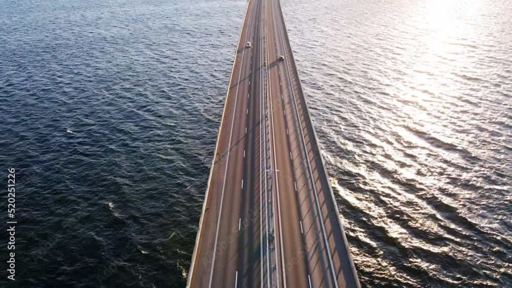 Drone flying over an Oresund bridge at the sunset in summer. Cinematic shot of long tunnel bridge between Sweden and Denmark. Cars driving on a huge bridge shot from the top. High quality 4k footage